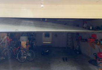 Interior garage view of off track steel sectional garage door before professional repair in Irving, TX