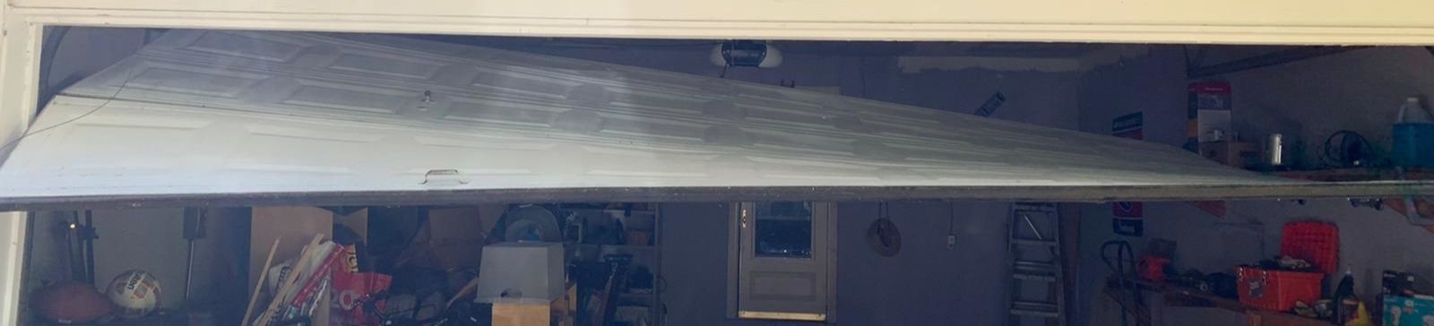 Interior garage view of off track steel sectional garage door before professional repair in Irving, TX